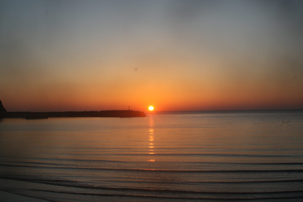 白鶴浜の海に沈む夕日と穏やかな波の風景